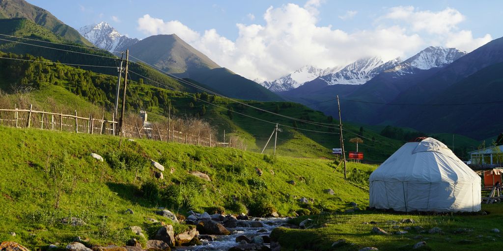 white tent on green grass field near mountain during daytime